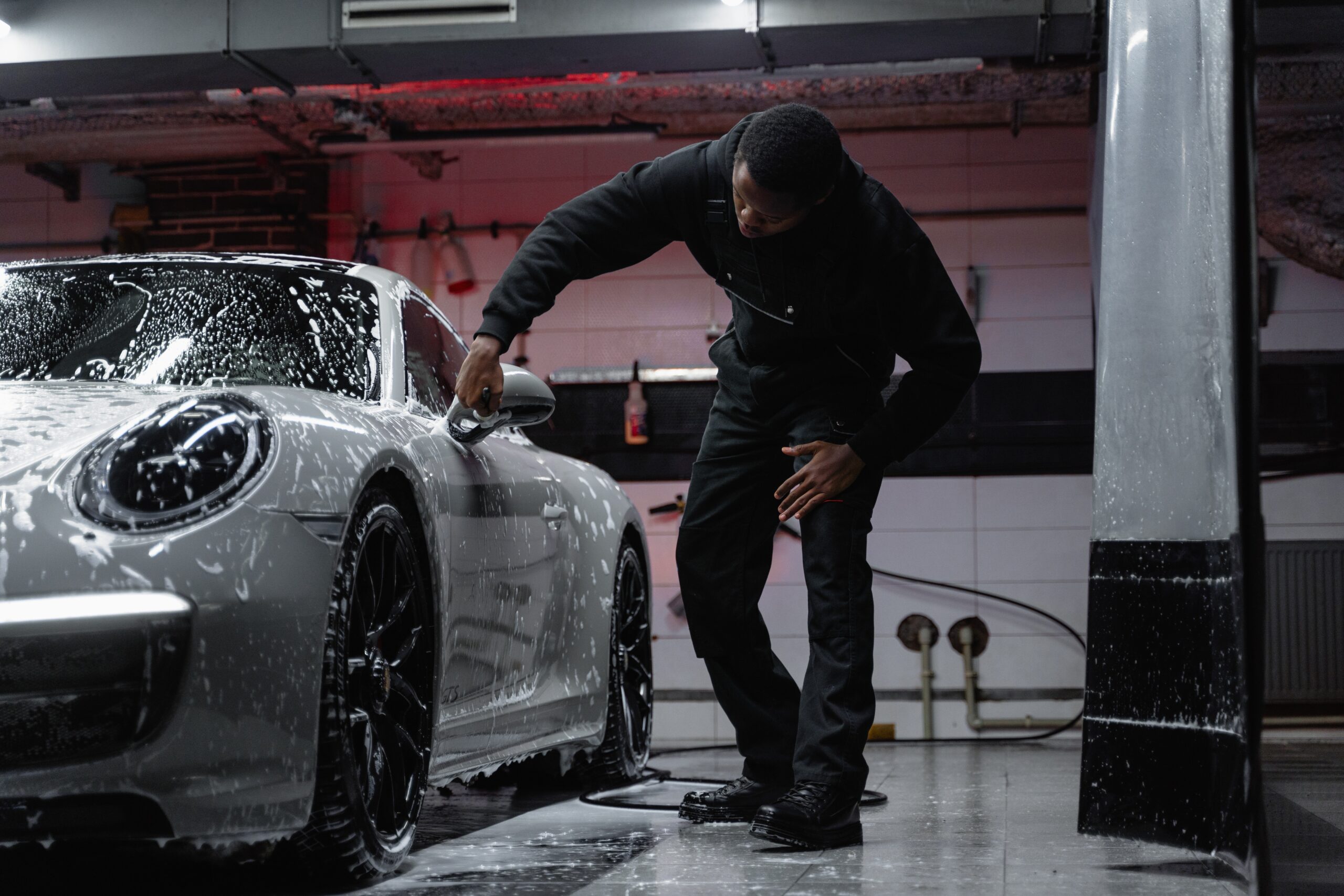 Bilden visar en person som tvättar bilen. Bilschampo med vax är praktiskt för snygga resultat av biltvätten.